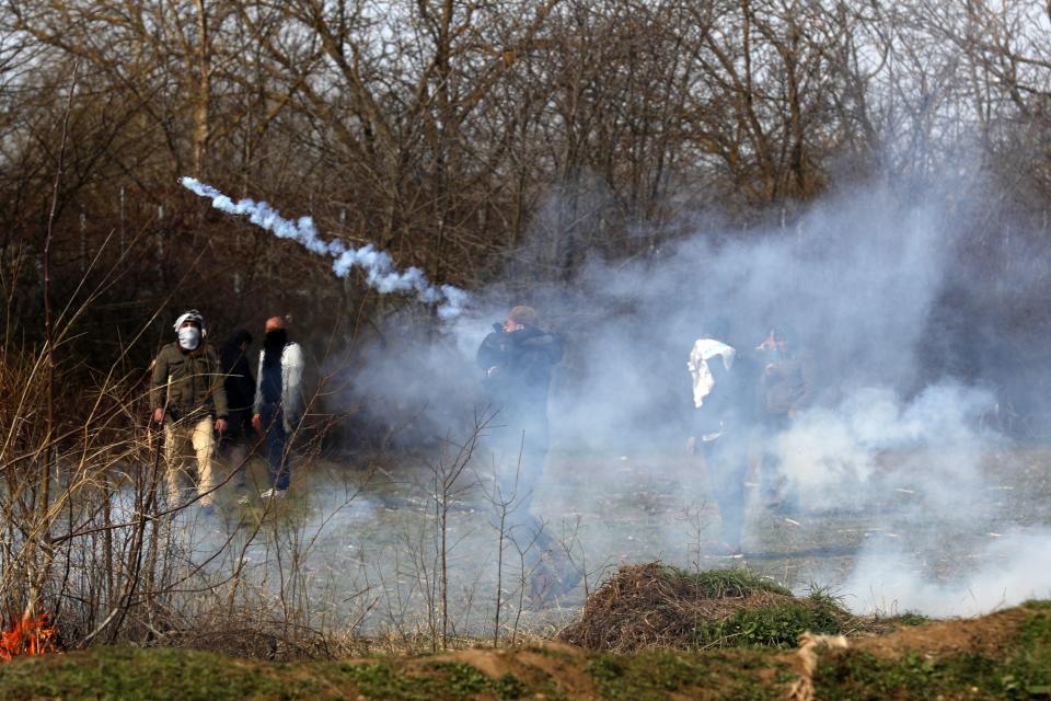 A migrants throws a tear gas at Greek police during clashes at the Turkish-Greek border near the Pazarkule border gate in Edirne, Turkey on Monday, March 2, 2020.Thousands of migrants and refugees massed at Turkey's western frontier, trying to enter Greece by land and sea after Turkey said its borders were open to those hoping to head to Europe. (AP Photo/Darko Bandic)