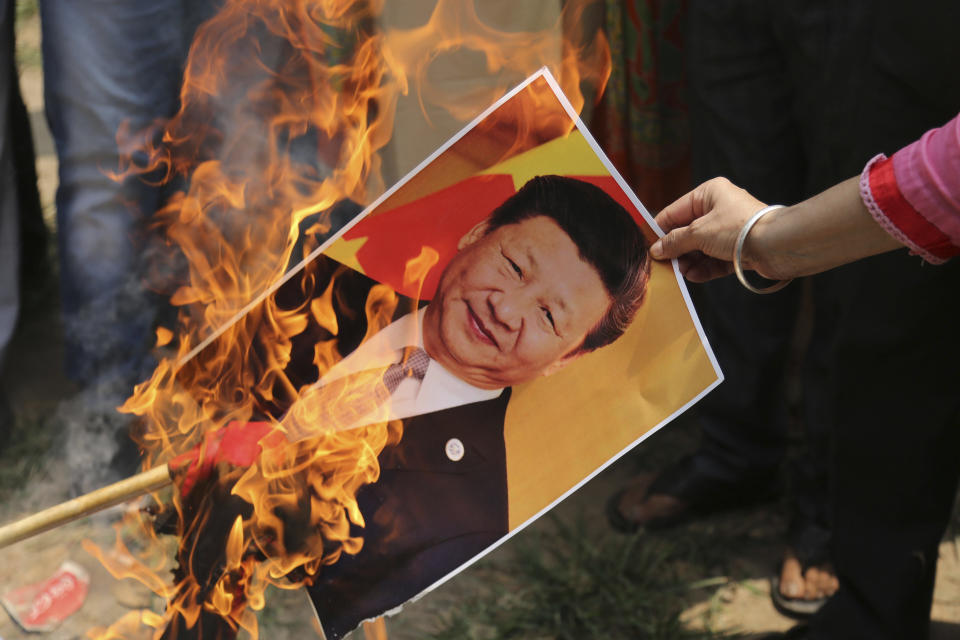 A Bharatiya Janata Party activist burns a photograph of Chinese President Xi Jinping during a protest in Jammu, India, Wednesday, July.1, 2020. Indian TikTok users awoke Tuesday to a notice from the popular short-video app saying their data would be transferred to an Irish subsidiary, a response to India's ban on dozens of Chinese apps amid a military standoff between the two countries. The quick workaround showed the ban was largely symbolic since the apps can’t be automatically erased from devices where they are already downloaded, and is a response to a border clash with China where 20 Indian soldiers died earlier this month, digital experts said. (AP Photo/Channi Anand)