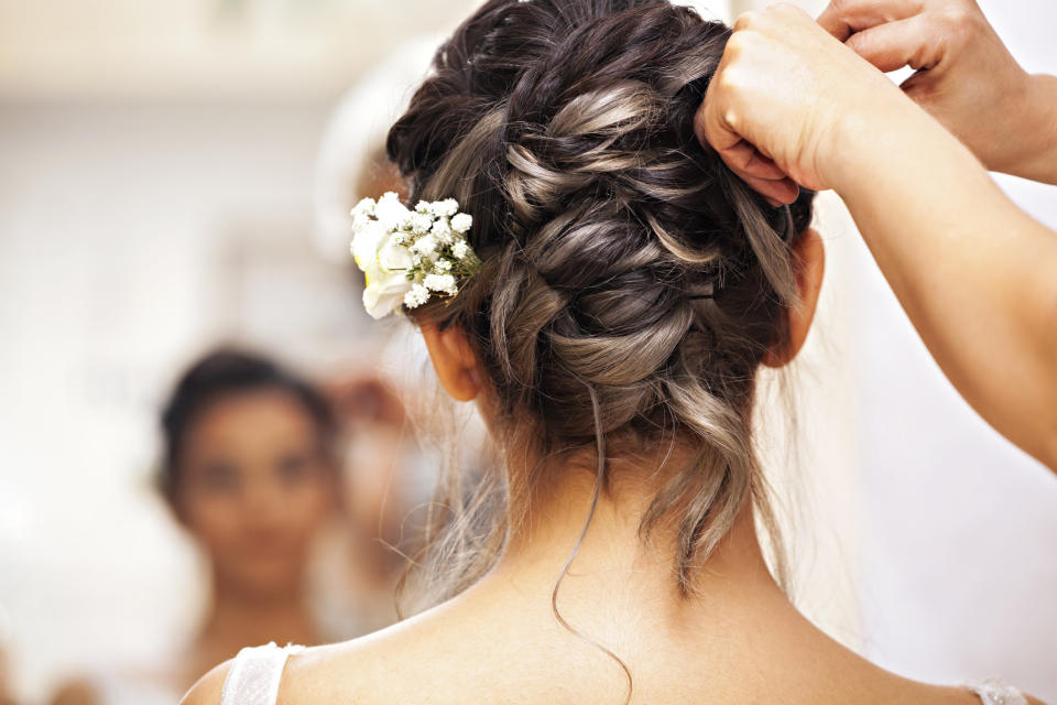 A stylist puts flowers into a bride's hair