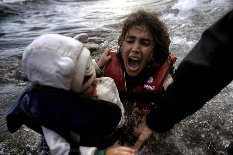 A woman falling into the water with her child as they disembark off a dinghi as refugees and migrants arrive at the Greek island of Lesbos after crossing the Aegean sea from Turkey