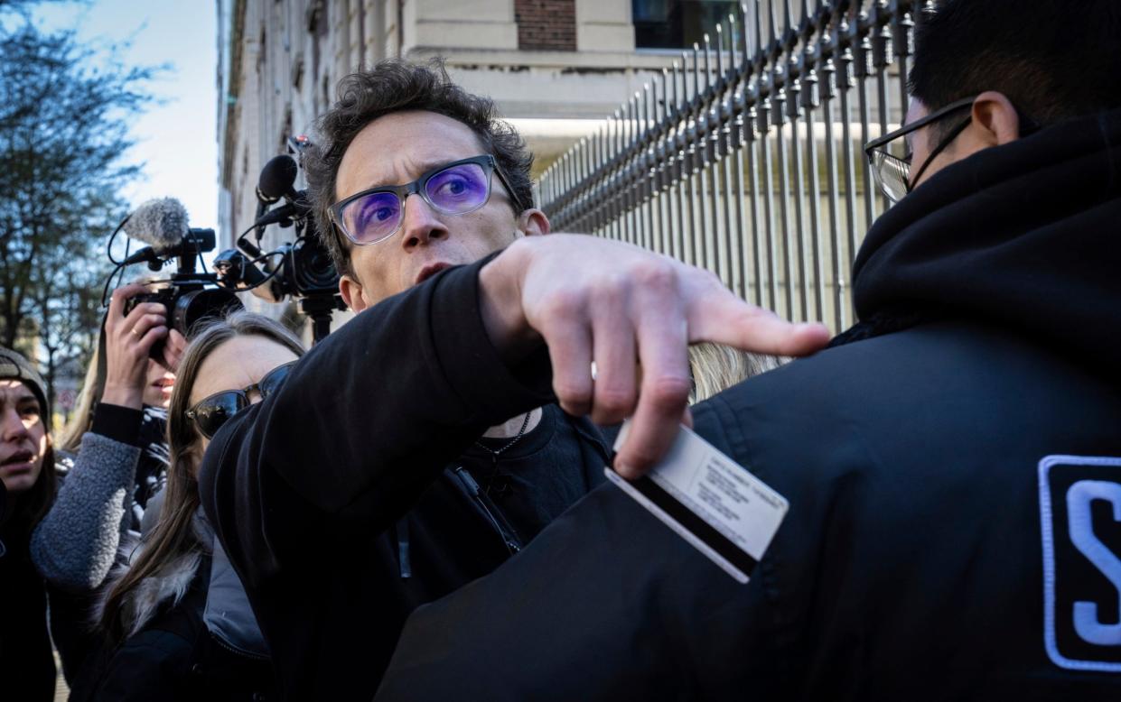 Prof Davidai holds his campus keycard aloft while a university worker keeps him out of the campus and photographs are taken