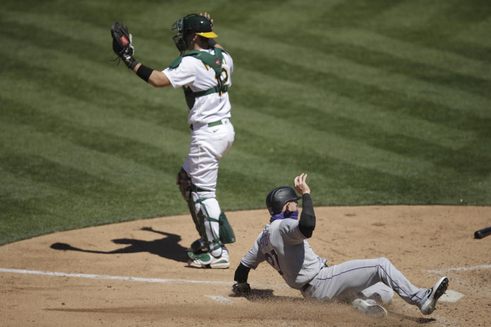 Colorado Rockies' Trevor Story, right, scores past Oakland Athletics catcher Sean Murphy (12) during the eighth inning of a baseball game, Wednesday, July 29, 2020, in Oakland, Calif. (AP Photo/Ben Margot)