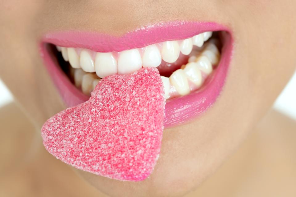 Heart shape candy on beautiful woman macro mouth