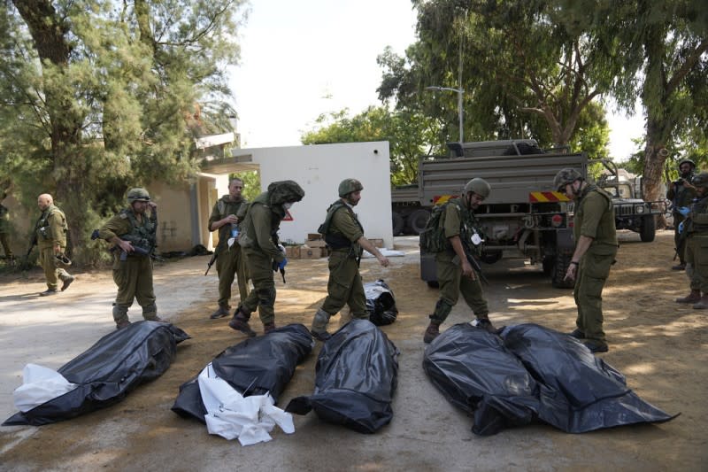 <cite>2023年10月10日，以色列士兵在卡法阿扎基布茲經過被哈瑪斯殺害的民眾屍體旁。 （美聯社）</cite>