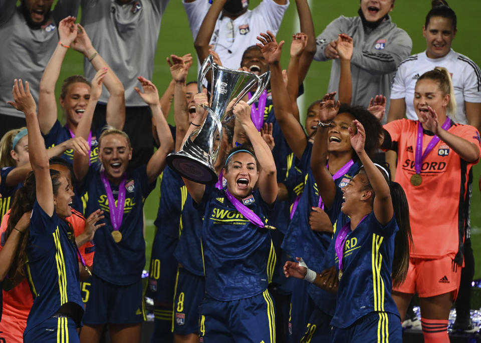 Lyon player Jodie Taylor and her teammates celebrate with trophy after winning the Women's Champions League final soccer match between Wolfsburg and Lyon at the Anoeta stadium in San Sebastian, Spain, Sunday, Aug. 30, 2020. Lyon won the match 1-3. (Gabriel Buoys/Pool via AP)