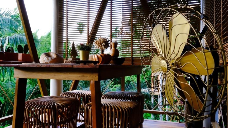 Old-fashioned metal fan on patio with wood furniture