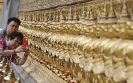 A Chinese tourist takes a picture at Wat Phra Kaeo (Emerald Buddha Temple) as they visit the Grand Palace in Bangkok March 23, 2015. REUTERS/Chaiwat Subprasom