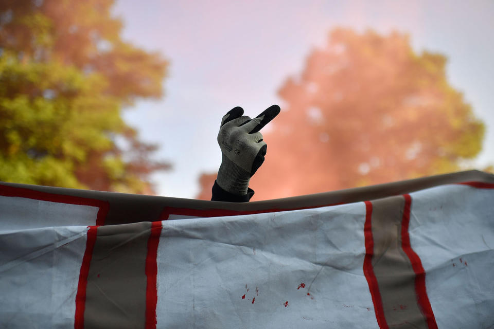 <p>A protester raises a gloved fist in a one fingered gesture over a banner as people take part in the “Welcome to Hell” protest march on July 6, 2017 in Hamburg, Germany. (Photo: Alexander Koerner/Getty Images) </p>