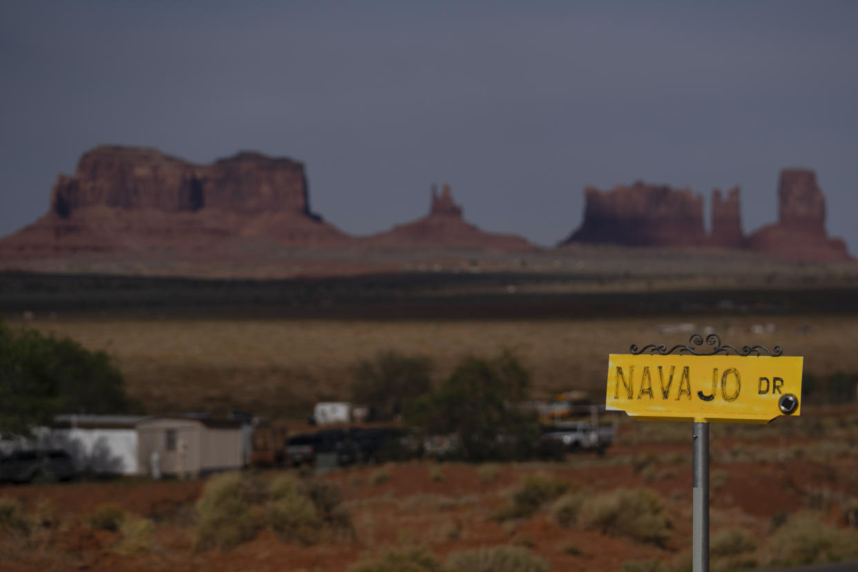 FILE - A sign marks Navajo Drive, as Sentinel Mesa, homes and other structures in Oljato-Monument Valley, Utah, on the Navajo Reservation, stand in the distance, on April 30, 2020. The Supreme Court appears to be split in a dispute between the federal government and the Navajo Nation over water from the drought-stricken Colorado River. The high court heard arguments Monday, March 20, 2023, in a case that states argue could upend how water is shared in the Western U.S. if the court sides with the tribe. (AP Photo/Carolyn Kaster, File)