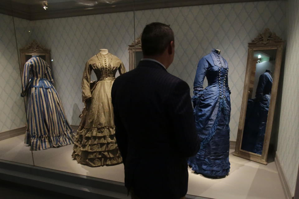 A journalist looks at women's afternoon dresses of the 19th century during the press day of the Impressionism and Fashion exhibition in at the Orsay museum in Paris, Friday, Sept. 21, 2012. To coincide with Paris Fashion week, a new and highly original exhibit called "Impressionism and Fashion" opens at the Musee d'Orsay. It uses famous works of art to explore how at the dawn of impressionism, and as an emblem of "modernite" fashion, and how people dressed, became one of the main themes in art. The exhibition will open September 25, 2012 and last till January 2013. (AP Photo/Michel Euler)