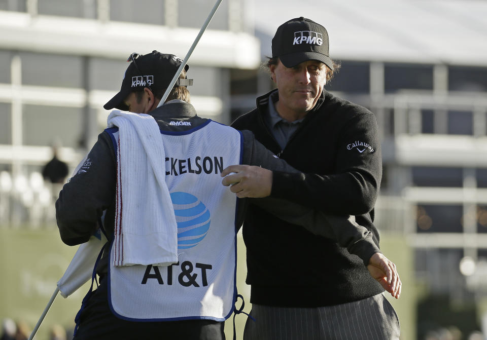 Phil Mickelson is embraced by his caddie and brother Tim Mickelson on the 18th green of the Pebble Beach Golf Links after winning the AT&T Pebble Beach Pro-Am golf tournament Monday, Feb. 11, 2019, in Pebble Beach, Calif. (AP Photo/Eric Risberg)