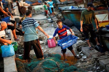 A Palestinian boy carries a container containing fish as he works with fishermen at the seaport of Gaza City September 26, 2016. Picture taken September 26, 2016. REUTERS/Mohammed Salem