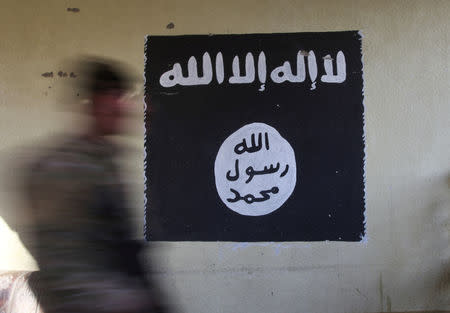 FILE PHOTO: A member of the Iraqi rapid response forces walks past a wall painted with the black flag commonly used by Islamic State militants, at a hospital damaged by clashes during a battle between Iraqi forces and Islamic State militants in the Wahda district of Mosul, Iraq, January 8, 2017. REUTERS/Alaa Al-Marjani/File Photo