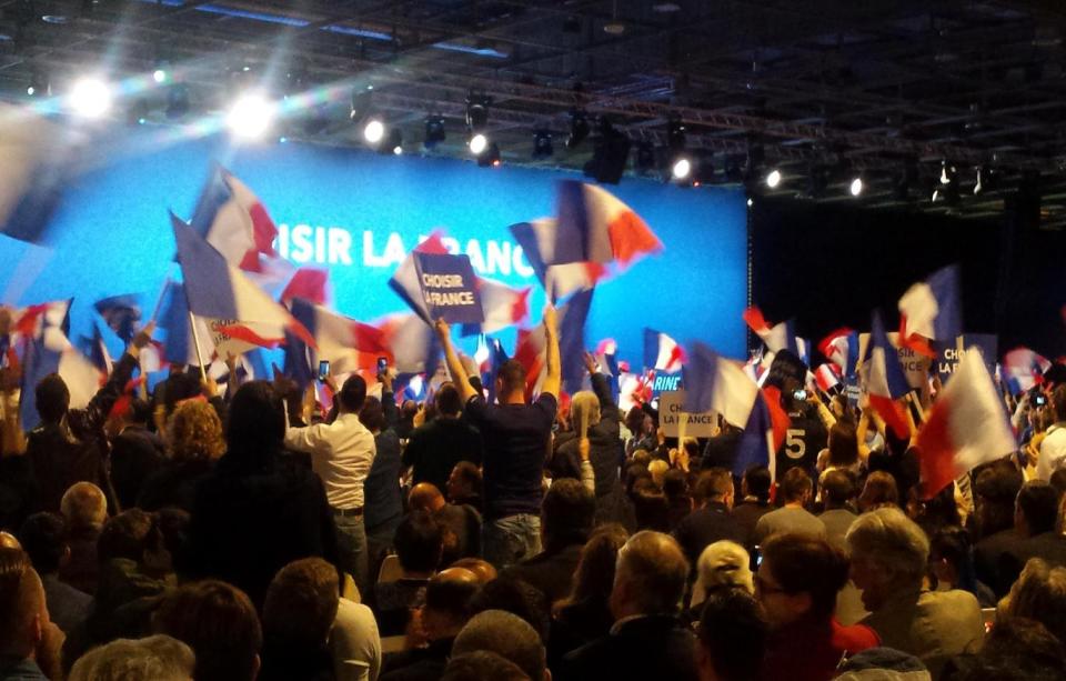 Marine Le Pen supporters cheer and wave their flags (The Independent)