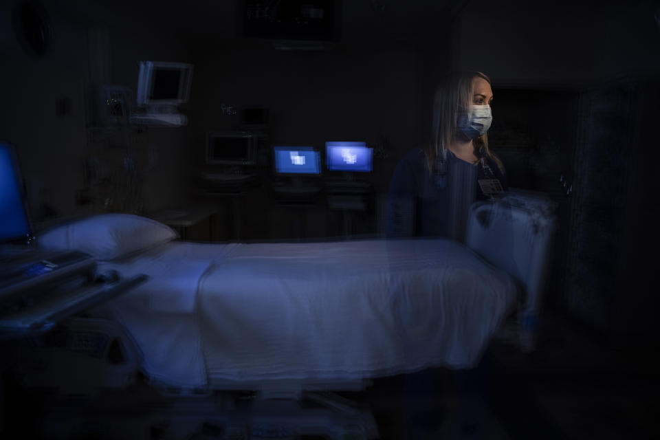 In this photo created with an in-camera multiple exposure, registered nurse Jamie Corcoran, part of a group of nurses who had been treating coronavirus patients in an intensive care unit, stands for a photo in the empty COVID-19 ICU at Providence Mission Hospital in Mission Viejo, Calif., Tuesday, April 6, 2021. As an ICU nurse the last five years, Corcoran got used to seeing death. She dealt with it by remaining detached. With COVID-19, detachment wasn't possible. (AP Photo/Jae C. Hong)