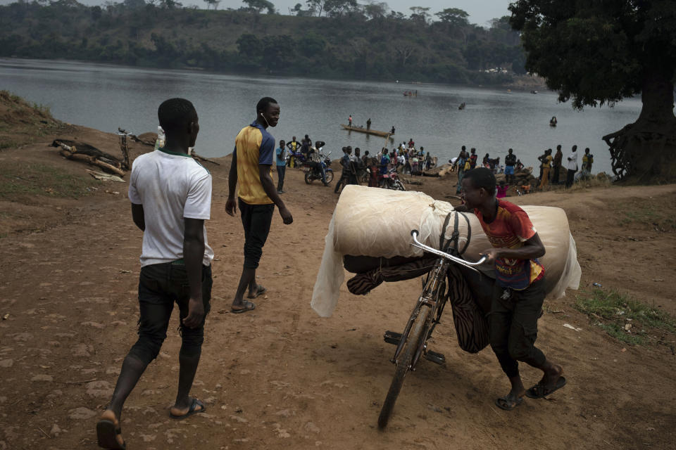 Jeremy Kowomando, 32, and his 14-large family, cross the Mbomou river back into Bangassou, Central African Republic, from Ndu in the Democratic Republic of the Congo, where they had taken refuge, Sunday Feb. 14, 2021. "For more than a month we received no aid," says Kowomando, explaining why he was returning. An estimated 240,000 people have been displaced in the country since mid-December, according to U.N. relief workers, when rebels calling themselves the Coalition of Patriots for Change launched attacks, causing a humanitarian crisis in the already unstable nation. (AP Photo/Adrienne Surprenant)