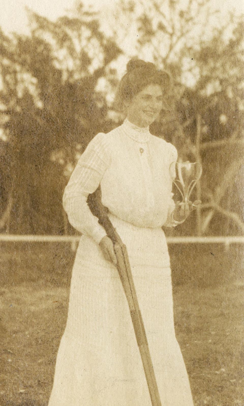 A woman identified as Edith McBride holds her shotgun and a trophy at the Florida Gun Club.