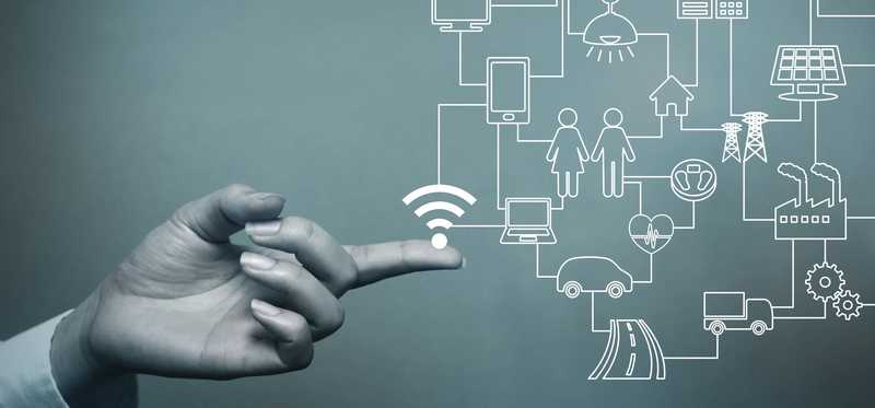 Human hand touching a digital grid of IoT devices.