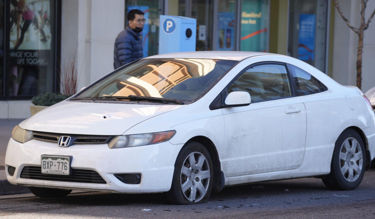 A Honda Civic parked along Alaska Drive has a bullet hole through the hood and a flat, left-front tire Tuesday, Dec. 28, 2021 in Lakewood, Colo., as it sits near one of the scenes of a shooting spree that left five people dead—including the suspected shooter Monday evening—and left three more people wounded. The spree spread from the core of Denver to the western suburb of Lakewood where the suspect was shot and killed by police near a busy intersection in a bustling shopping district. (AP Photo/David Zalubowski)