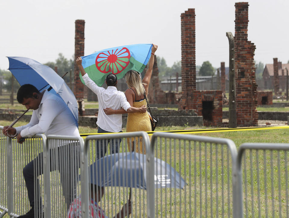 People display a Romani flag to commemorate the Roma and Sinti people killed by Nazi Germany in World War II, during ceremonies, in Oswiecim, Poland, Friday Aug. 2, 2019. The American civil rights activist Rev. Jesse Jackson gathered Friday with survivors at the former Nazi death camp of Auschwitz-Birkenau to commemorate an often forgotten genocide — that of the Roma people. (AP Photo/Czarek Sokolowski)