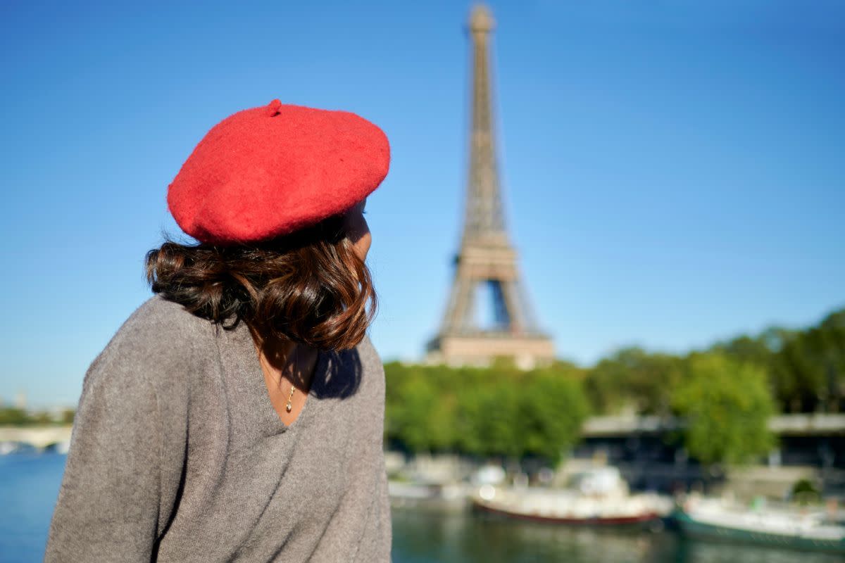 woman wearing a red beret looking off toward the Eiffel Tower in Paris