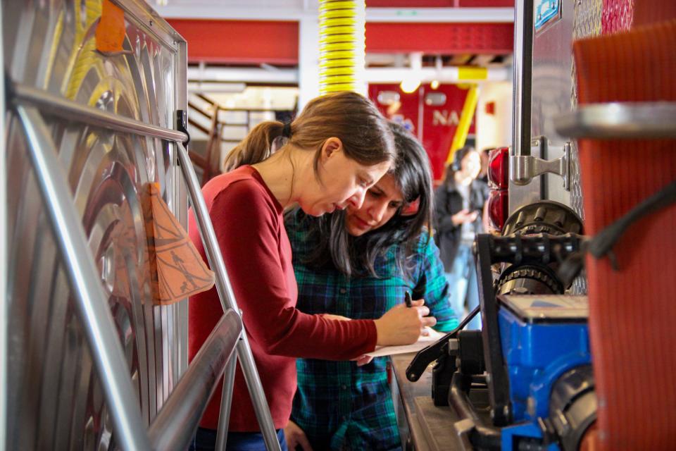 Michigan State University professor Courtney Carignan, left, and Nantucket PFAS Action Group co-founder Ayesha Khan lean on a fire engine while examining protocols for a research study on March 28, 2022.