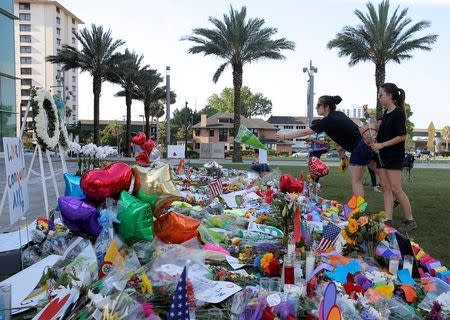 A woman throws a bouquet of flowers at a memorial for the victims of the shooting at the Pulse gay nightclub in Orlando, Florida, June 14, 2016. REUTERS/Jim Young