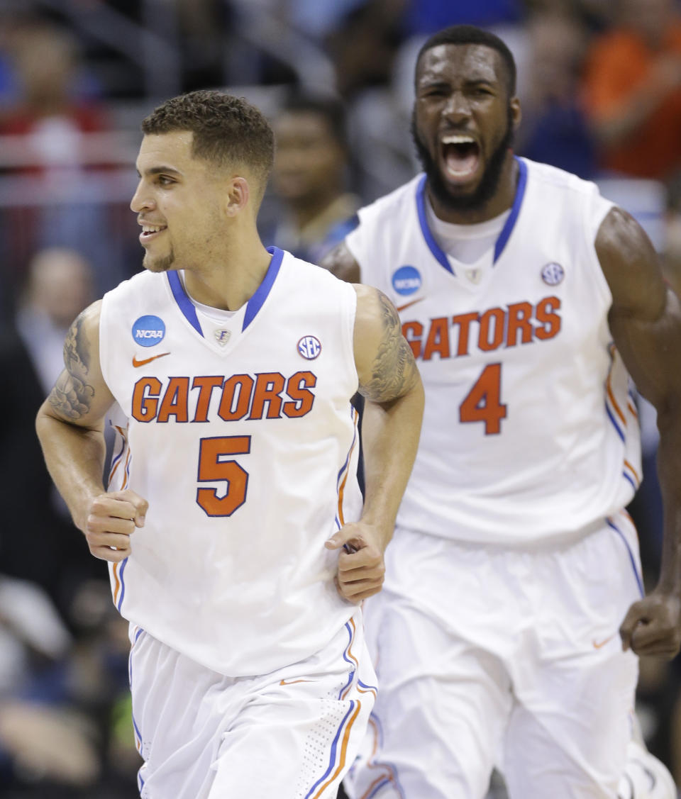Florida guard Scottie Wilbekin (5) and Florida center Patric Young (4) run off the court after Wilbekin made a 3-point shot against the Pittsburgh at the buzzer to end the first half in a third-round game in the NCAA college basketball tournament in Orlando, Fla., Saturday, March 22, 2014. (AP Photo/John Raoux)