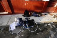 A migrant sleeps-in by his bicycle on the street in Huixtla, Chiapas state, Mexico, at daybreak Tuesday, Oct. 26, 2021, as the group of migrants he's traveling with, mostly from Central America, use the day to rest during their trek by foot toward the U.S. (AP Photo/Marco Ugarte)