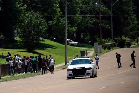 A police car drives by a group of people the day after violent clashes between police and protesters broke out on streets overnight in Memphis