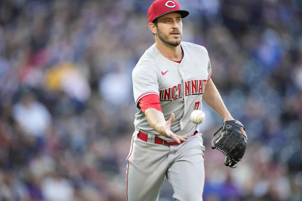 Cincinnati Reds starting pitcher Connor Overton tosses the ball to first baseman Joey Votto to put out Colorado Rockies' Connor Joe in the fourth inning of a baseball game Saturday, April 30, 2022, in Denver. (AP Photo/David Zalubowski)