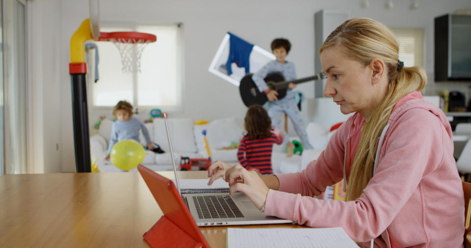 Mother working from home while her kids playing at the background