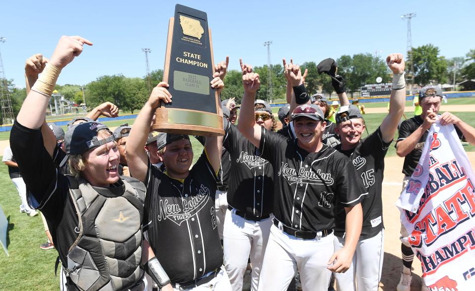 The New London baseball team celebrates with the trophy after winning the 2022 Class 1A state baseball championship against Remsen St. Mary at Merchants Park in Carroll.