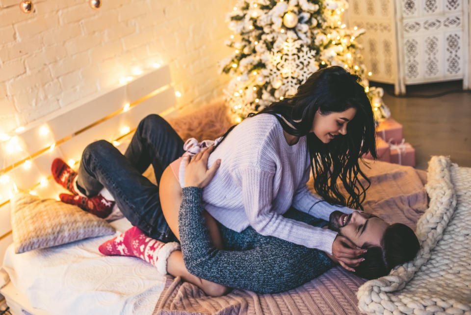 Passionate romantic couple spending time before New Year near beautiful Christmas tree at home