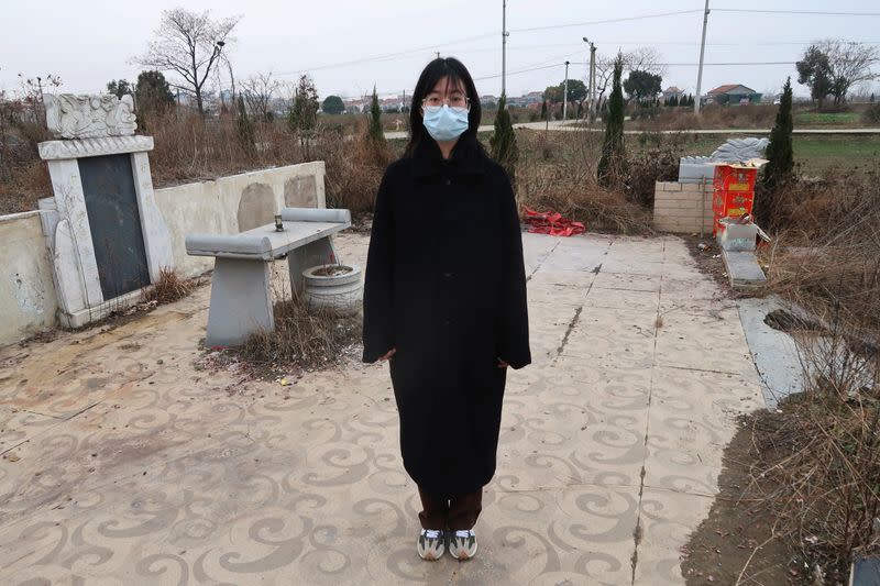 Deng Wei poses for a picture in front of her grandmother's and father's tombs in Wuhan