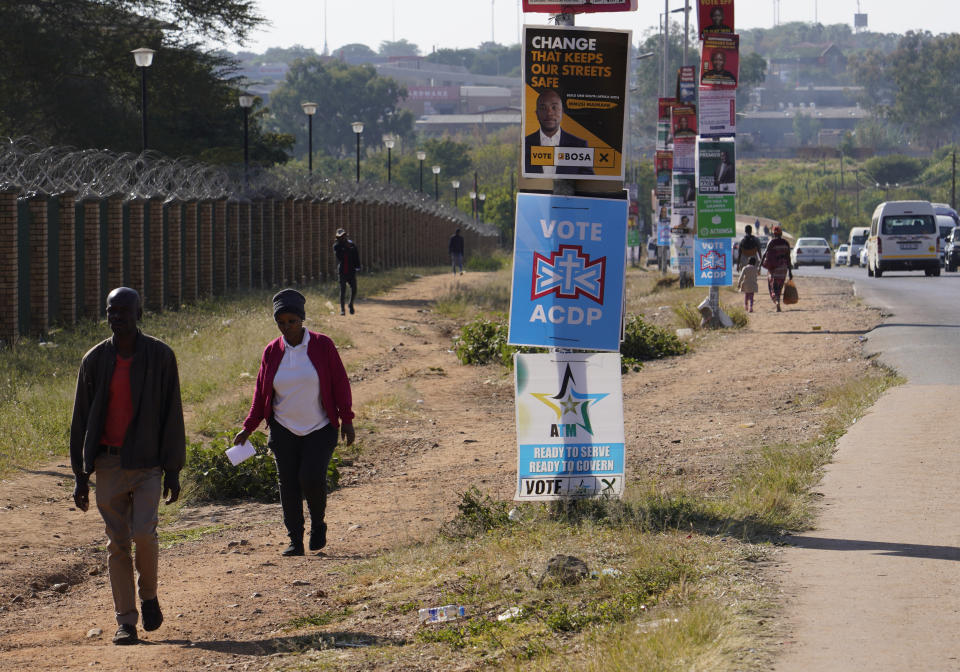 People walk along a street lined with election posters in the Hammanskraal township, Pretoria, South Africa, Wednesday, May 22, 2024. Hammanskraal’s problems are a snapshot of the issues affecting millions and driving a mood of discontent in South Africa that might force its biggest political change in 30 years in next week’s national election. (AP Photo/Denis Farrell)