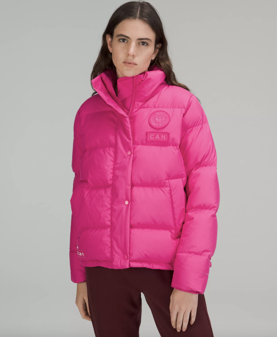 brunette woman wearing pink coat, Team Canada Women's Wunder Puff Jacket COC Logo (photo via Lululemon)