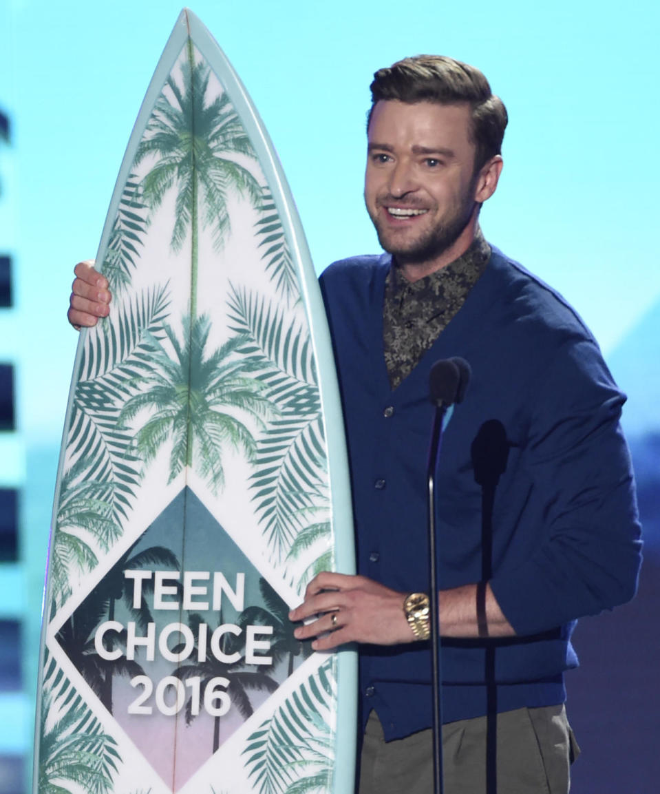 Justin Timberlake accepting his Artist of the Decade surfboard in a royal blue cardigan 