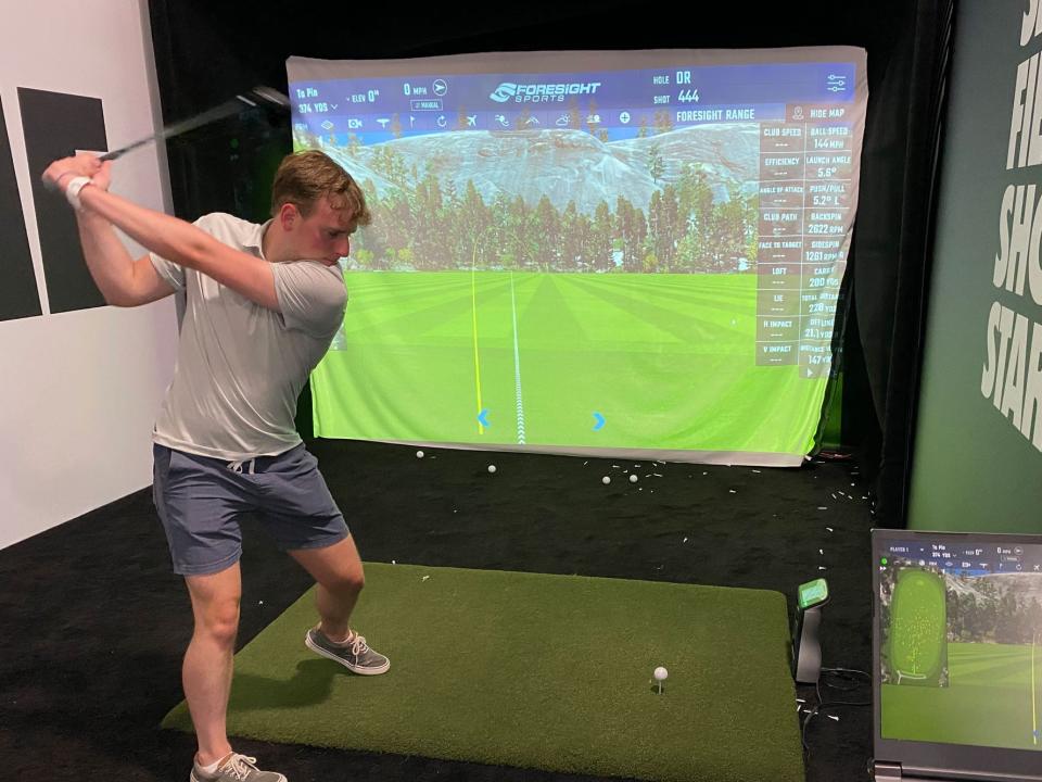 Jacob takes a swing on a simulator at LIV Golf's event in Bedminster, New Jersey.