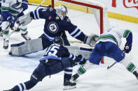 Winnipeg Jets goaltender Laurent Brossoit (39) makes a save against Vancouver Canucks' Pius Suter (24) as Rasmus Kupari (15) defends during the third period of an NHL hockey game Thursday, April 18, 2024, in Winnipeg, Manitoba. (John Woods/The Canadian Press via AP)