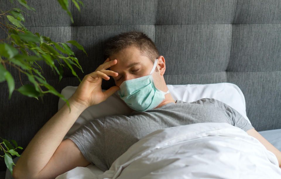 Sick man with medical mask lying in bed. Coronavirus quarantine concept.