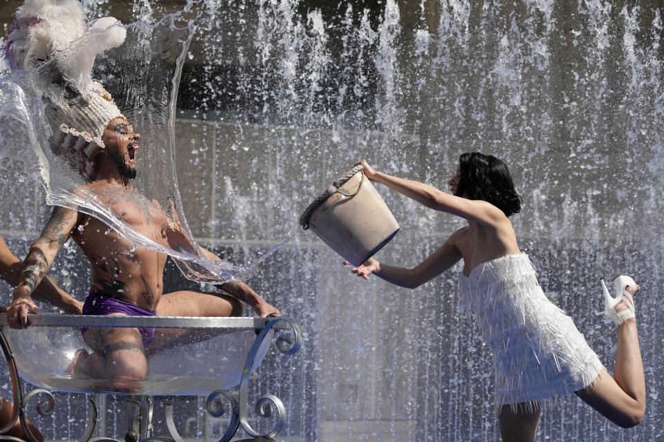 ADDS TROUPE'S NAME - Members of the Australian cabaret & circus troupe Briefs, cool down in a fountain on the Southbank in London, Tuesday, July 19, 2022. Britain shattered its record for highest temperature ever registered Tuesday, with a provisional reading of 39.1 degrees Celsius (102.4 degrees Fahrenheit), according to the country's weather office — and the heat was only expected to rise. (AP Photo/Frank Augstein)