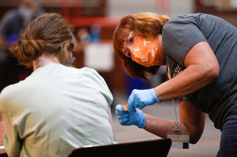 Julie Brannum puts a bandage on a patient after administering a vaccine at a coronavirus vaccination clinic for the public and students held in Neyland Stadium in August. The COVID-19 legislative package passed by the state allows for institutions who are at risk of losing federal funding to apply for exemption.