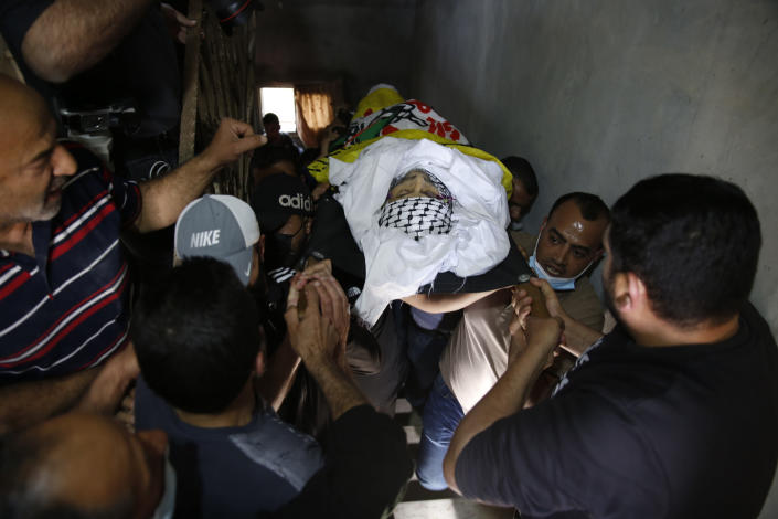 Palestinians carry the body of Osama Mansour during his funeral, in the village of Biddu near the West Bank city of Ramallah, Tuesday, April 6, 2021. Mansour was killed by Israel soldiers at a temporary vehicle checkpoint in the occupied West Bank near Jerusalem. The military said the soldiers thwarted an attempted car-ramming attack in the village of Bir Nabala. But the man's wife, who was in the car with him and was wounded by the gunfire, said the couple followed the soldiers' instructions and posed no threat. (AP Photo/Majdi Mohammed)