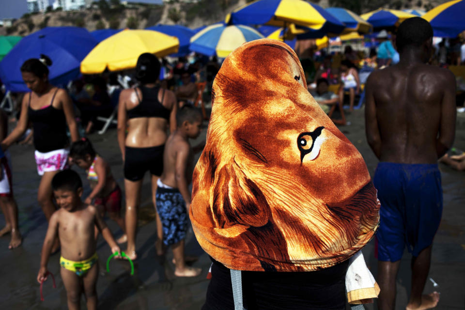 In this Jan. 22, 2013 photo, a woman covers herself with a towel on Agua Dulce beach in Lima, Peru. While Lima's elite spends its summer weekends in gate beach enclaves south of the Peruvian capital, the working class jams by the thousands on a single municipal beach of grayish-brown sands and gentle waves. Until the mid-20th century, Lima's lower classes couldn't afford beach-going, said Juan Pacheco, a historian of the city. Road-building to the coast solved that, and the rich began to largely abandon Lima's beaches to the poorer set. (AP Photo/Rodrigo Abd)