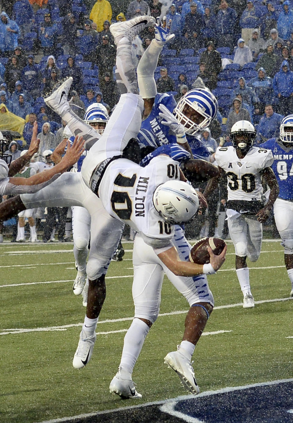 Central Florida quarterback McKenzie Milton (10) dives over Memphis defensive back Josh Perry (4) as he scores the go-ahead touchdown on a 7-yard run during the second half of an NCAA college football game Saturday, Oct. 13, 2018, in Memphis, Tenn. Central Florida won 31-30. (AP Photo/Mark Zaleski)