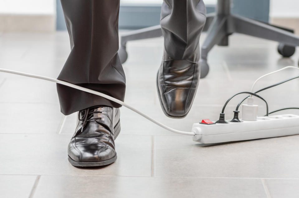 Person tripping over an office power cord. Safety hazard highlighted