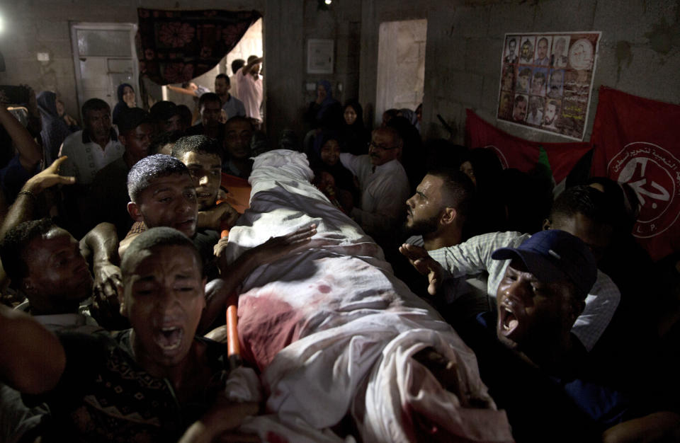 Palestinian mourners carry the body of 23 year-old Hamas fighter, Ahmad Morjan, mourn at the family home during his funeral, in the Jabaliya refugee camp, Northern Gaza Strip, Tuesday, Aug. 7, 2018. The Israeli military said it targeted a Hamas military post in northern Gaza after militants opened fire, and Hamas said two of its fighters were killed. (AP Photo/Khalil Hamra)