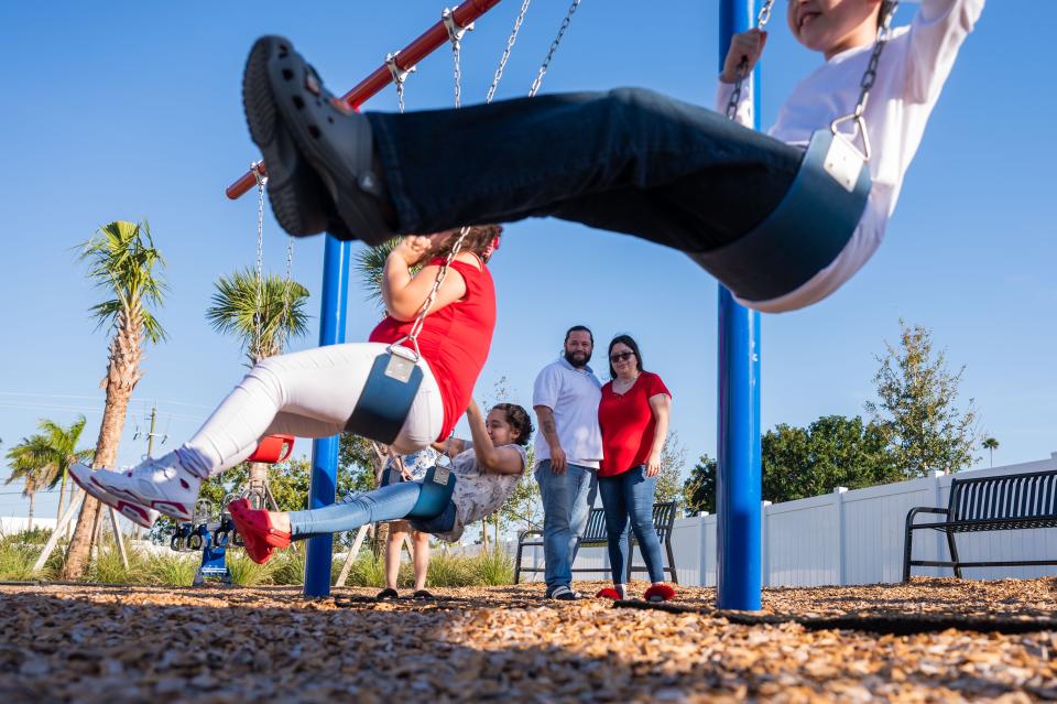 Nelson and Raysa Torres watch three of their children, Anaya, left, Janelliz, center, and Nelson Jr., play on a swing set in the back yard of their new townhome.