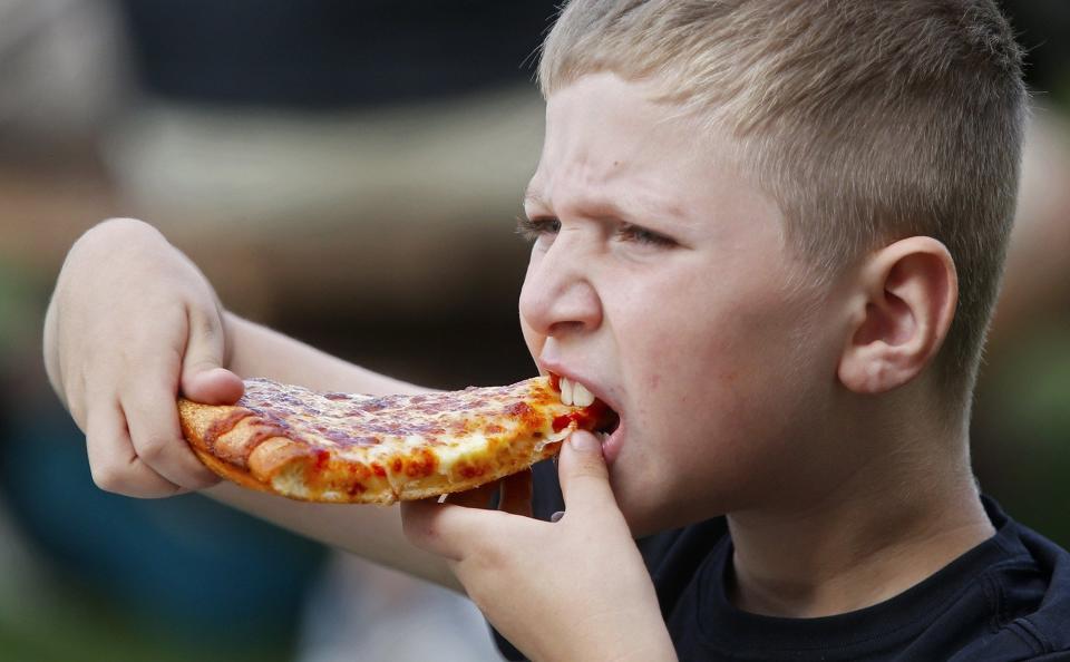Brailyn Clark, 7, of Ellet, munches pizza at the 2019 Akron Pizza Fest at Lock 3 Park.